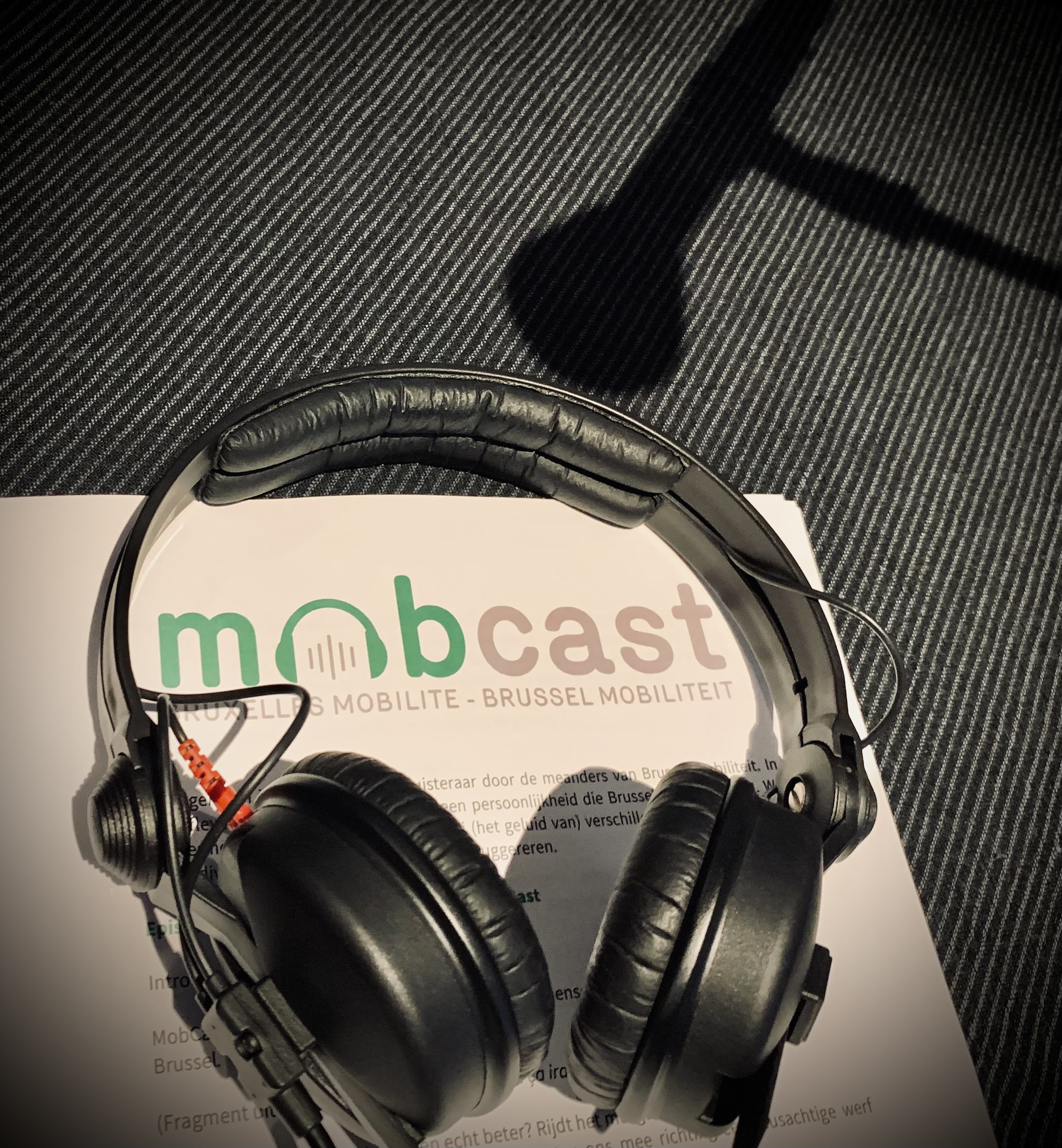 Casque audio déposé sur une page où il est indiqué « Mobcast – Bruxelles Mobilité – Brussel Mobiliteit » et l’ombre d’un micro.